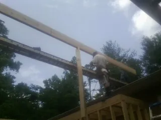 Carpenter setting a ridge beam over a new addition frame — Ice Dam Removal by Roofing Brothers in Olney Springs