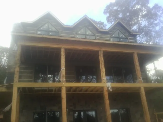 Dormers and porch framing on a large log home under construction — Roof Coating work by our crew in Olney Springs