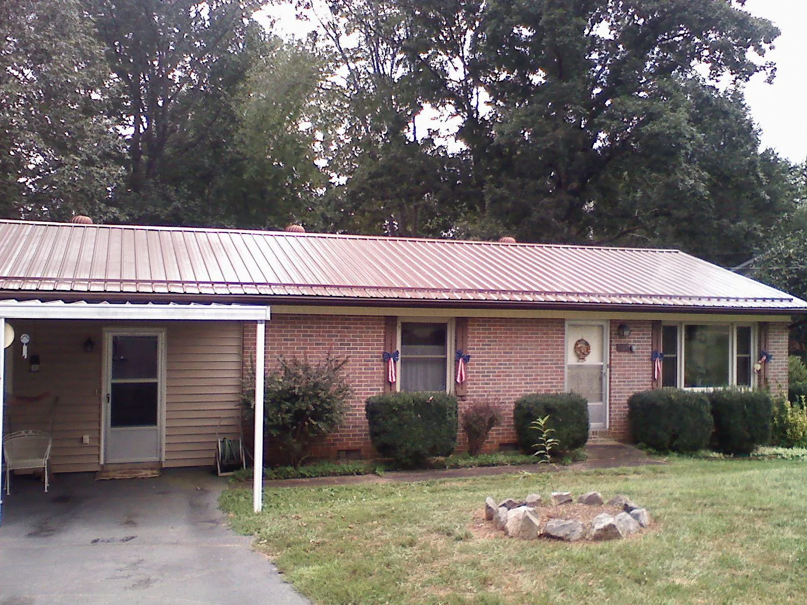 Bronze metal roof and carport on a brick ranch home — Roof Repair work by our crew in Olney Springs