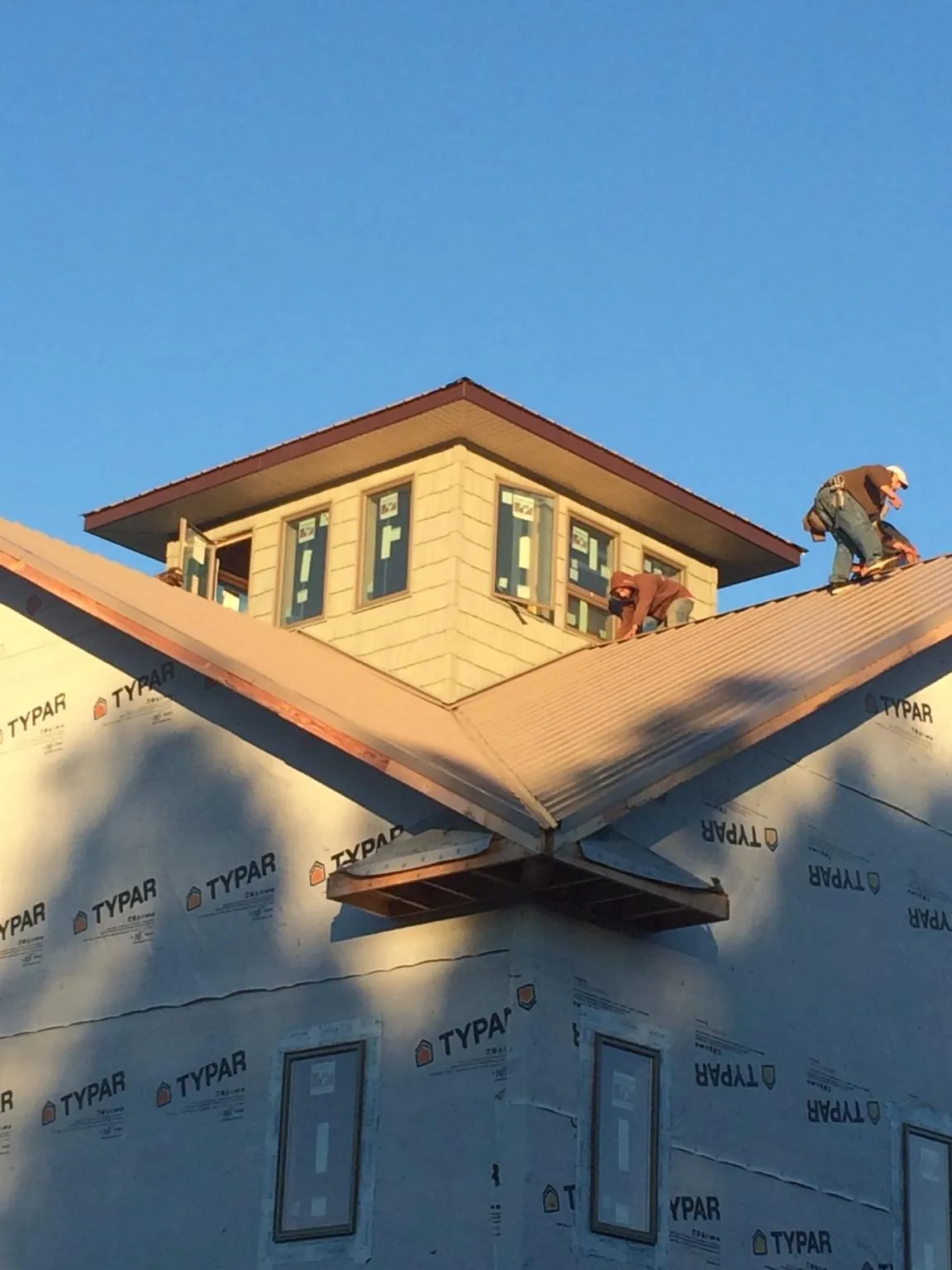 Roofers working around a rooftop cupola on a new metal roof at sunset — Roof Waterproofing in Olney Springs by Roofing Brothers
